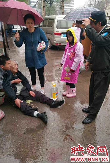 女孩為倒地老人撐傘。