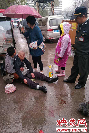 女孩為倒地老人撐傘。