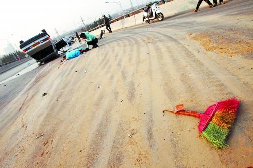 被撞的環(huán)衛(wèi)工躺在地上，身上蓋著藍(lán)色布塊，現(xiàn)場除散落的汽車碎片外，還留有被撞斷的掃帚。