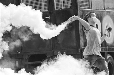 12月2日，泰國曼谷，一名反政府示威者在總理府附近向負責執(zhí)勤的警察投擲催淚彈。英拉請求示威者不要再試圖占領(lǐng)政府工作部門，不要逼迫政府工作人員選邊站。