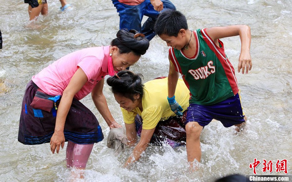 7月9日，村民在小河里摸魚(yú)搶魚(yú)。譚凱興 攝