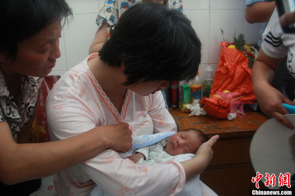 圖為久別重逢，獲救嬰兒母親悉心撫摸愛子。張一辰 攝