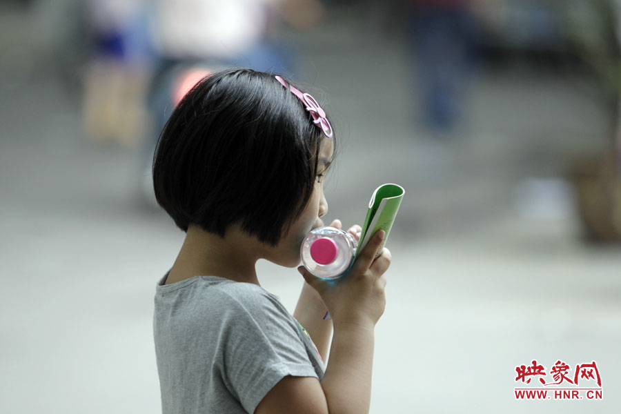 6月7日，鄭州回中考點(diǎn)，一名孩子拿著一瓶礦泉水，等待哥哥走出考場(chǎng)