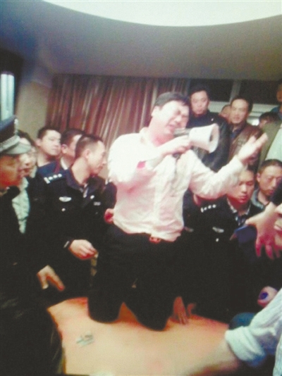 　4月19日，泰州市濱江工業(yè)園區(qū)管委會招待中心，一男子跪在酒桌上喊話求饒。李根 攝