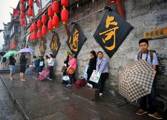 　4月29日上午11時20分，一些游客和古城當(dāng)?shù)氐木用穸阍谝粋€酒吧的屋檐下避雨。這些當(dāng)?shù)鼐用褚詾橛慰团恼罩\生，一場降雨讓他們的生意更加清淡。