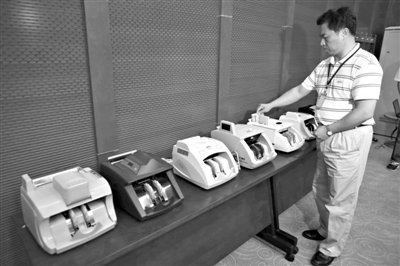 昨日，央行工作人員用各種驗鈔機對C1F9假幣進行測試，機器均能及時作出異常報警反應(yīng)。新京報記者 浦