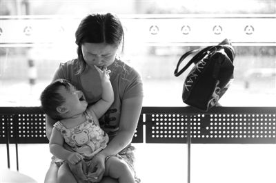 昨日，肯德基京廣中心店門(mén)口，姜女士提起跟養(yǎng)父母的關(guān)系時(shí)落淚，懷中9個(gè)月的女兒笑著跟她玩。新京報(bào)記者 薛珺 攝