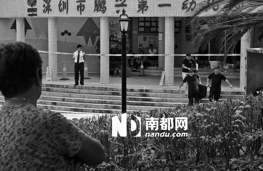 →7月19日，鵬興花園第一幼兒園門前，民警在現(xiàn)場進(jìn)行完勘查取證后，園長和保安的尸體被運(yùn)走。南都記者 徐文閣 攝
