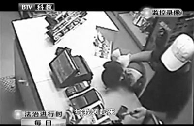 戴帽男子一手掐住加油站營業(yè)員，一手持發(fā)令槍指向另一營業(yè)員，要求“把錢給我裝起來”。