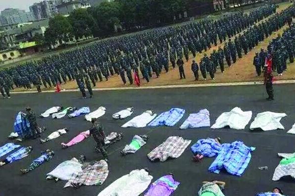 20多名女生躺在瀝青跑道上，身上嚴嚴實實地裹著棉被，接受太陽的照曬。