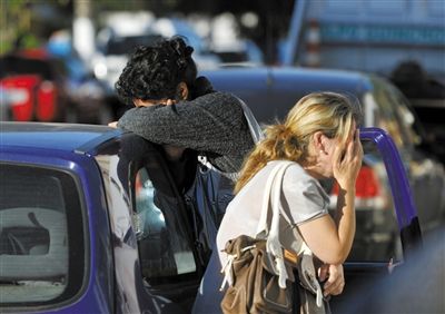 27日，遇難者親友在火災(zāi)現(xiàn)場(chǎng)旁哭泣。