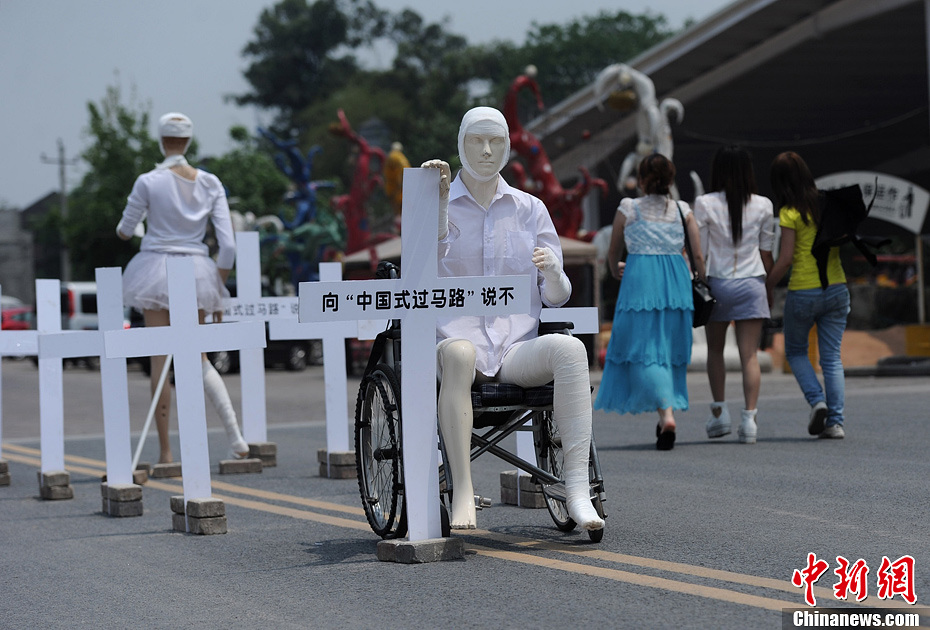 4月16日，重慶市洋人街上擺放著兩個受了傷的塑料人像“模特”，旁邊十字架上寫著向“中國式過馬路”說不