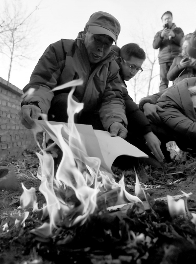 李三仁在兒子墳前焚燒再審無罪判決文書的復印件。新華社發(fā)