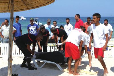 6月26日，在突尼斯蘇塞，救生員和醫(yī)務(wù)人員在發(fā)生襲擊事件的海灘運送一名死者的遺體。新華社發(fā)