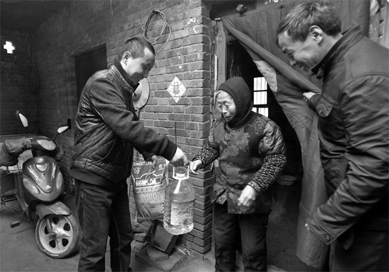 吳乃浩（左）給村里老人送去過(guò)年的年貨