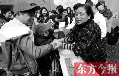 昨日，鄭大四附院的大樓前，“面人鄭”鄭玉芬（右）向前來捐款的殘疾人表示感謝