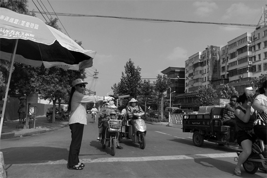 昨日，開封市區(qū)一名協(xié)管員在指揮群眾過馬路