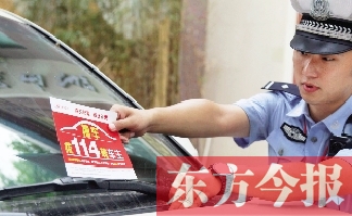 交警將“挪車(chē)請(qǐng)撥打114轉(zhuǎn)車(chē)主”的提示牌放在路邊?？康能?chē)上