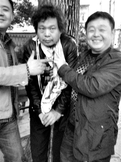 兩名接訪人員與患有癌癥的訪民段新德合影時(shí)，面帶笑容擺出勝利的手勢。