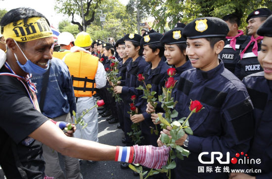 2013年12月03日,曼谷總理府與曼谷警署允許反政府示威民眾進(jìn)入,雙方進(jìn)入暫時“停戰(zhàn)”狀態(tài)迎接泰王生日。曼谷警察總署,女警們手持鮮花送給反政府示威民眾。圖片來源:Manish Swarup/東方IC
