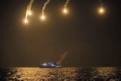 22日，搜救人員在照明彈的光亮下連夜搜救。