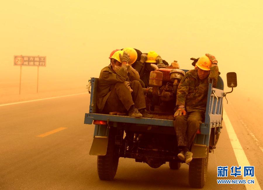 4月23日，一輛拉載公路施工人員的三輪車(chē)在沙塵暴中行駛在酒泉市瓜州縣城郊的公路上。