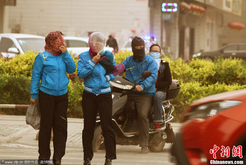 2014年04月23日，新疆維吾爾自治區(qū)吐魯番地區(qū)，市民戴著口罩行走在大風(fēng)沙塵中的吐魯番市街頭。