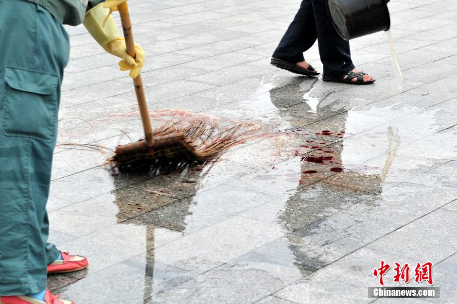 圖為環(huán)衛(wèi)工人在清理案發(fā)地點(diǎn)的血跡。