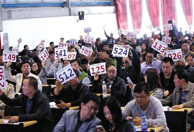 競(jìng)拍者正在練習(xí)舉牌動(dòng)作，以便拍賣時(shí)讓工作人員看清號(hào)牌。