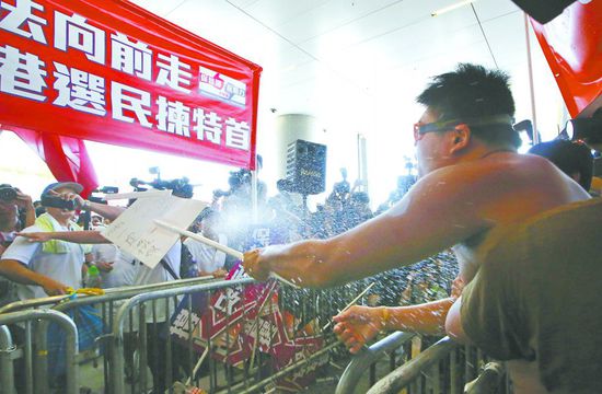 17日，在香港立法會外，一名反對政改的男子向支持派人群投擲標(biāo)牌。