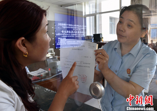 資料圖：2015年5月4日，河北石家莊市橋西區(qū)人民法院立案庭庭長齊燕正在為立案人辦理相關(guān)手續(xù)，完成整個過程只用了5分鐘。當(dāng)日是立案登記制改革首個工作日，該院共立案36件，立案率達到90%。中新社發(fā) 翟羽佳 攝