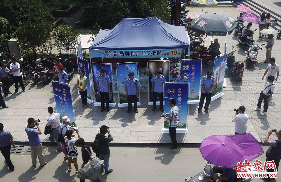 執(zhí)法人員用宣傳牌圍擋占道經(jīng)營(yíng)攤位。