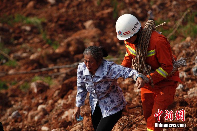 一位消防戰(zhàn)士將一位失去親人的老人扶離滑坡點。