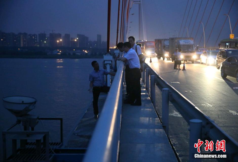 圖為武漢警方談判專家正在與翻爬至大橋外側(cè)護(hù)欄的劫持者談判。