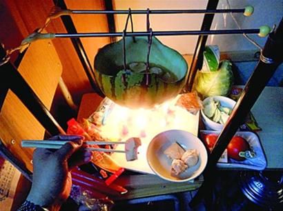 兩張椅子被面對面疊在一起，穿了兩根線的西瓜皮就懸空在椅腳中間，下面有蠟燭加熱，這就是西瓜火鍋。