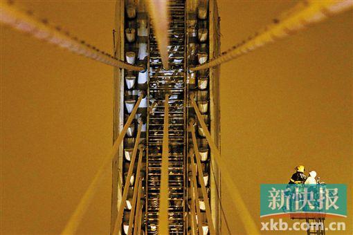 截至今日零時(shí)，男子仍未有下橋舉動(dòng)。圖為公安和消防人員乘消防云梯在高空上和男子交談。