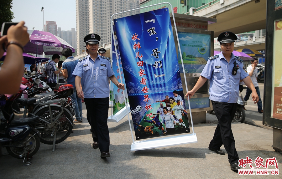 7月2日上午，鄭州市紫荊山地鐵站出入口，執(zhí)法人員抬著寫(xiě)有勸導(dǎo)語(yǔ)的宣傳板，前往占道經(jīng)營(yíng)攤位“圍觀執(zhí)法”
